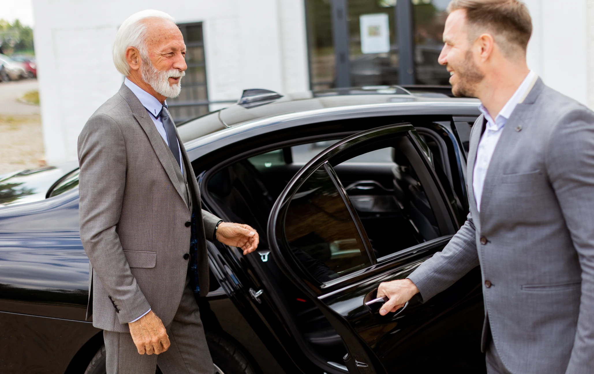 Businessmen greeting at luxury car